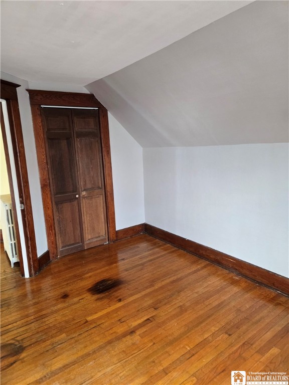 additional living space with radiator, baseboards, hardwood / wood-style floors, and lofted ceiling