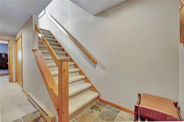 staircase with stone finish flooring, a baseboard radiator, and baseboards