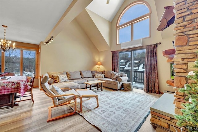 living area with high vaulted ceiling, light wood-style flooring, a notable chandelier, an AC wall unit, and baseboard heating