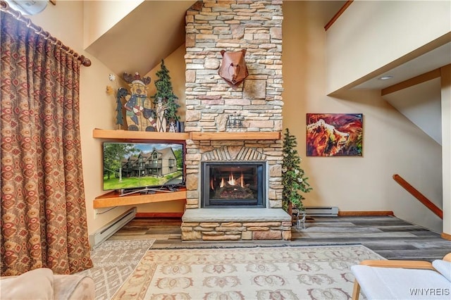 living room with baseboards, wood finished floors, a high ceiling, baseboard heating, and a fireplace