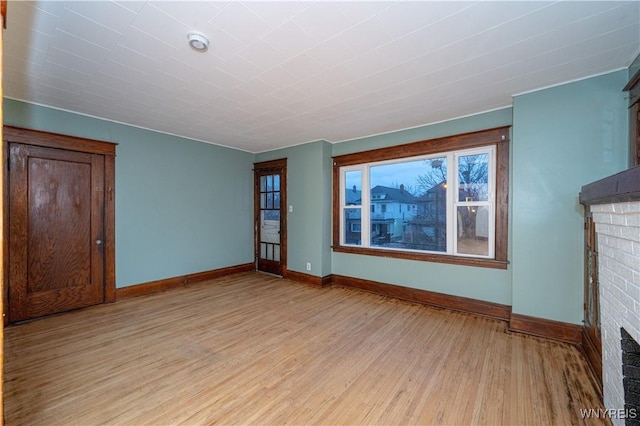 unfurnished living room featuring light wood finished floors, a fireplace, and baseboards