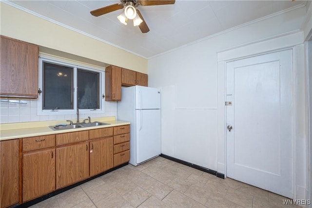 kitchen with tasteful backsplash, light countertops, crown molding, and freestanding refrigerator