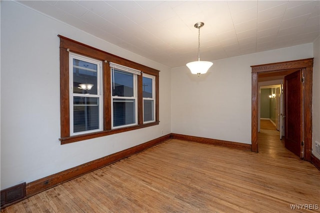 spare room with light wood-style floors, visible vents, and baseboards