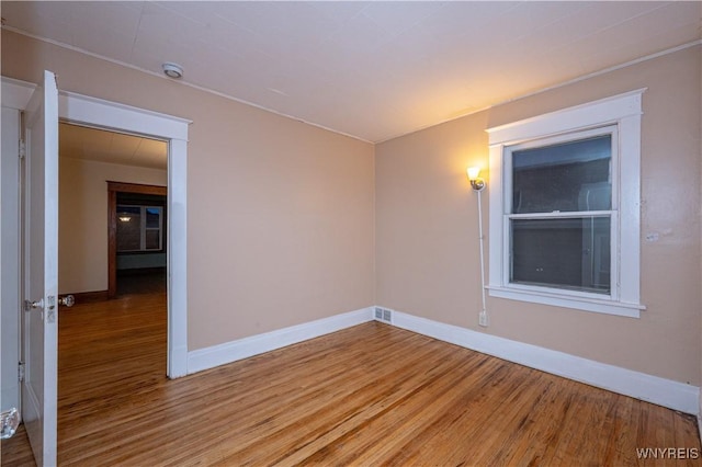 spare room with light wood-style flooring, visible vents, and baseboards