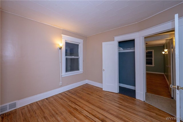 unfurnished bedroom with baseboards, a closet, visible vents, and wood finished floors