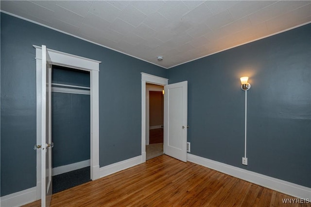 unfurnished bedroom with a closet, wood finished floors, and baseboards