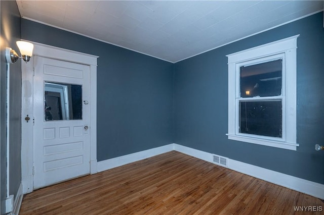 unfurnished room with visible vents, baseboards, and wood finished floors