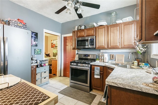 kitchen featuring light tile patterned floors, appliances with stainless steel finishes, light countertops, a textured ceiling, and a sink