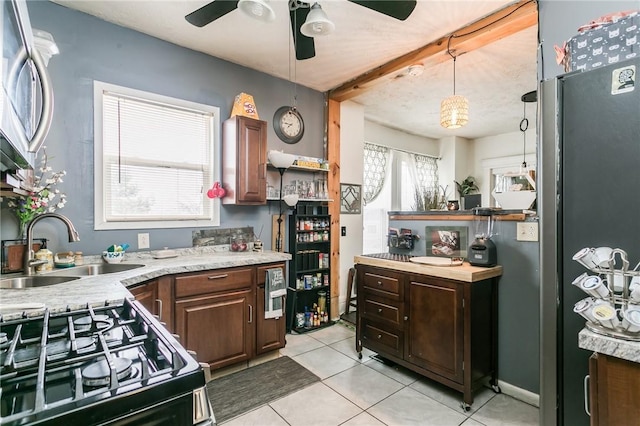 kitchen featuring light tile patterned floors, black gas range, a sink, a ceiling fan, and light countertops