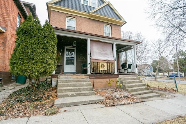 american foursquare style home with covered porch and brick siding