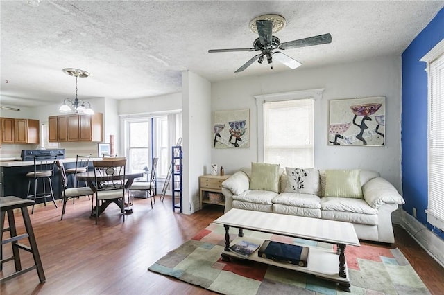 living area with a ceiling fan, a textured ceiling, baseboards, and wood finished floors