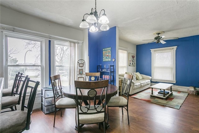 dining room featuring a textured ceiling, wood finished floors, and ceiling fan with notable chandelier