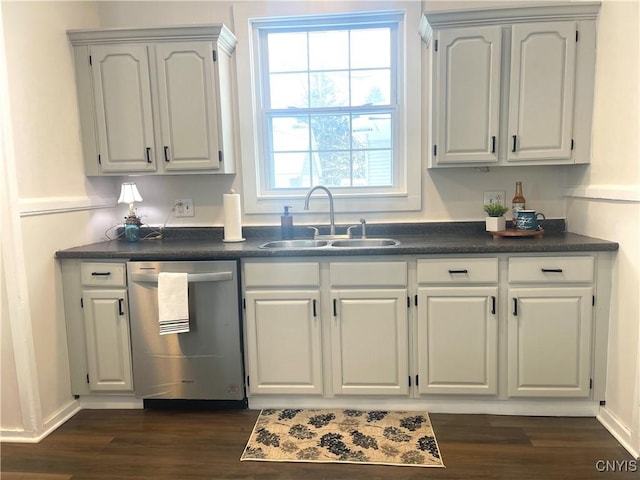 kitchen featuring dark wood-type flooring, a sink, baseboards, dishwasher, and dark countertops