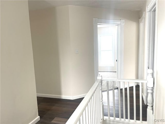 hallway with dark wood finished floors, an upstairs landing, and baseboards