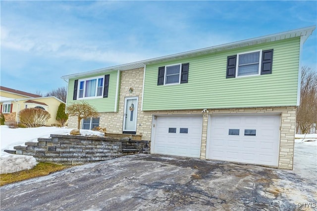 split foyer home with stone siding, aphalt driveway, and an attached garage