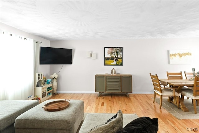 living area featuring light wood-style floors and baseboards