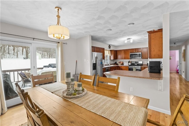 dining space with a notable chandelier, light wood-style flooring, and baseboards