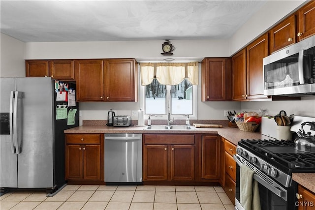 kitchen featuring light tile patterned floors, stainless steel appliances, a sink, and brown cabinets