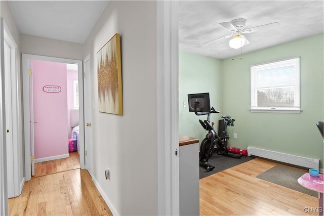 hallway with baseboards, a baseboard radiator, and light wood-style floors