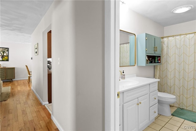 full bathroom with toilet, a shower with shower curtain, wood finished floors, vanity, and baseboards