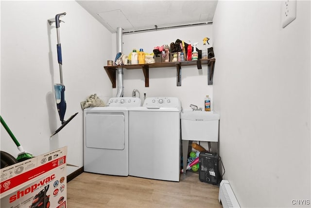 washroom with washer and dryer, laundry area, baseboard heating, and light wood finished floors