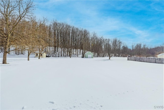 yard covered in snow with fence and an outbuilding