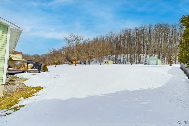 snowy yard featuring a detached garage and a wooden deck