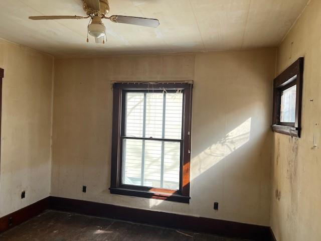 unfurnished room featuring ceiling fan and baseboards