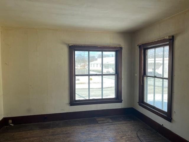 spare room featuring wood finished floors, a wealth of natural light, and baseboards