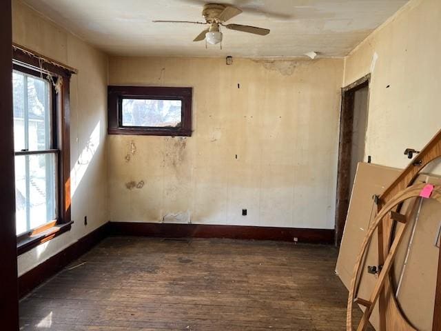 spare room with dark wood-style floors, ceiling fan, plenty of natural light, and baseboards