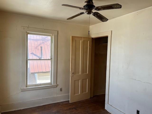 empty room featuring dark wood-style floors, plenty of natural light, baseboards, and ceiling fan