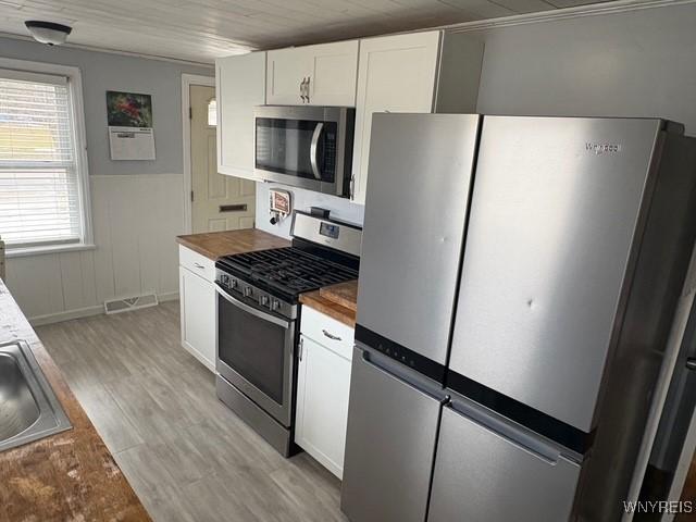 kitchen with butcher block counters, visible vents, light wood-style flooring, appliances with stainless steel finishes, and white cabinetry