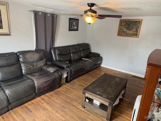 living room with a ceiling fan, baseboards, arched walkways, and wood finished floors