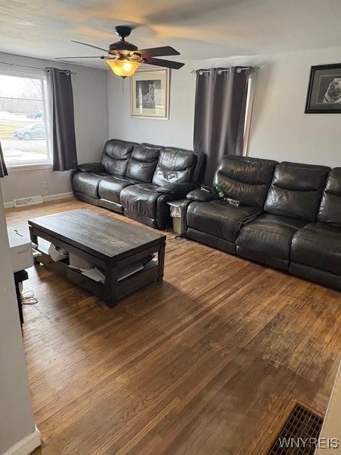 living area with a ceiling fan, baseboards, and wood finished floors