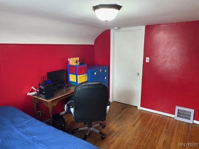 bedroom with lofted ceiling, baseboards, visible vents, and wood finished floors