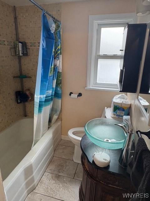 bathroom with shower / tub combo, baseboards, toilet, tile patterned flooring, and a sink