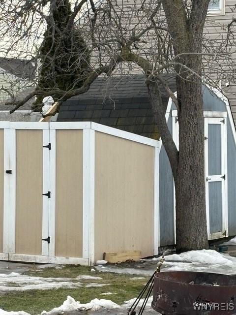 snow covered structure with an outbuilding and a shed