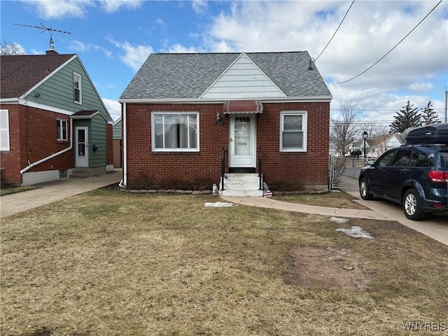 bungalow-style home featuring entry steps, a shingled roof, a front lawn, and brick siding