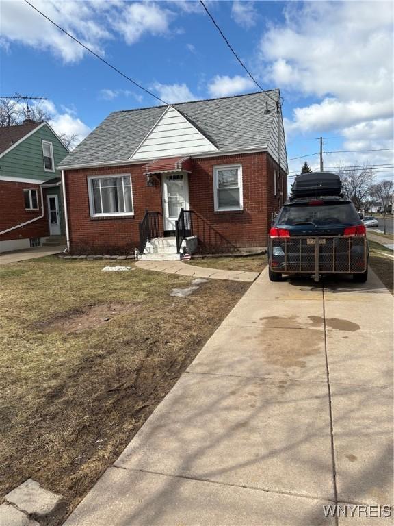 bungalow featuring driveway, brick siding, and roof with shingles