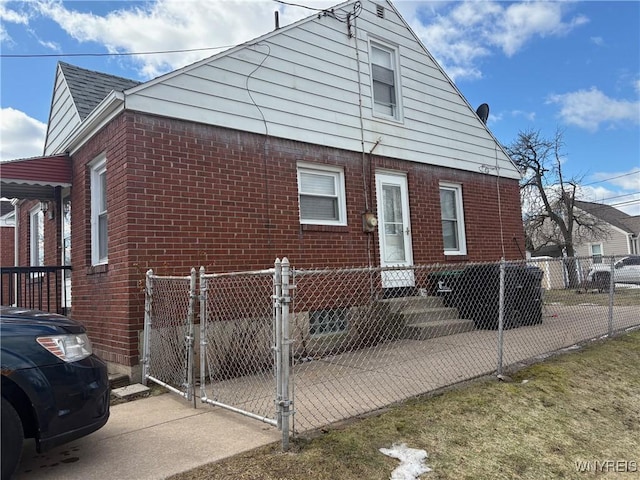 view of front of house featuring a fenced front yard, a gate, brick siding, and a shingled roof