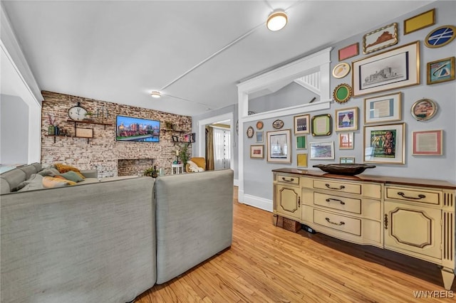 living room with light wood finished floors, baseboards, a fireplace, and an accent wall