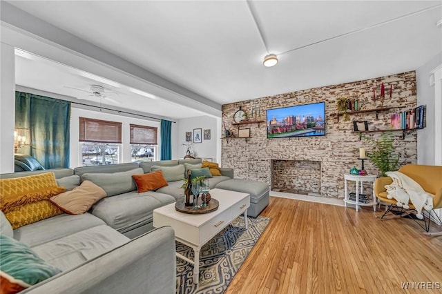 living room featuring ceiling fan, brick wall, and light wood-style floors