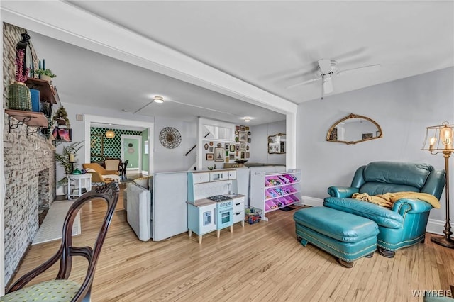 living room with stairs, a ceiling fan, and wood finished floors