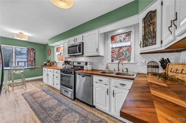 kitchen featuring white cabinets, butcher block counters, stainless steel appliances, and a sink