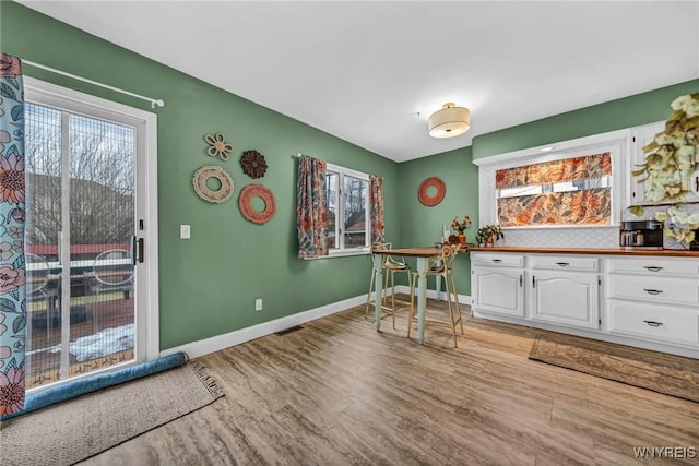 interior space with a healthy amount of sunlight, light wood-style flooring, white cabinetry, and baseboards