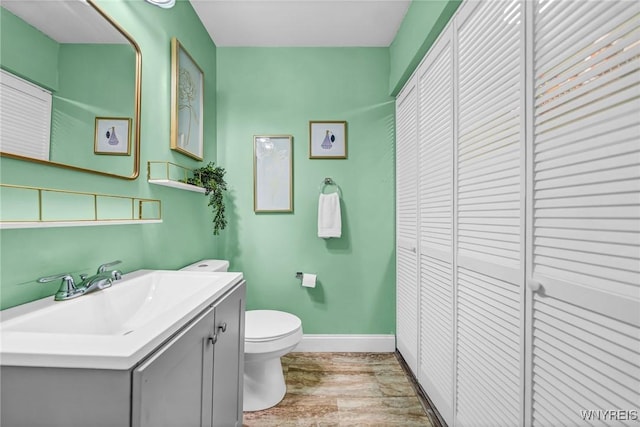 bathroom featuring a closet, baseboards, vanity, and toilet