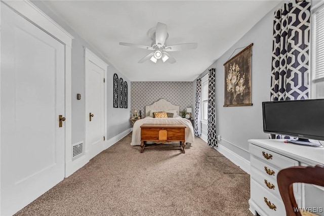 carpeted bedroom with wallpapered walls, visible vents, an accent wall, and baseboards