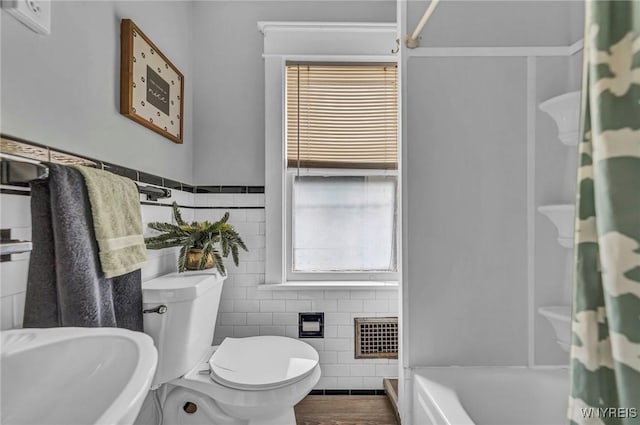 bathroom featuring tile walls, visible vents, toilet, a shower with shower curtain, and a sink