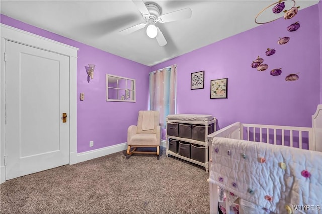 carpeted bedroom featuring a ceiling fan, a crib, and baseboards