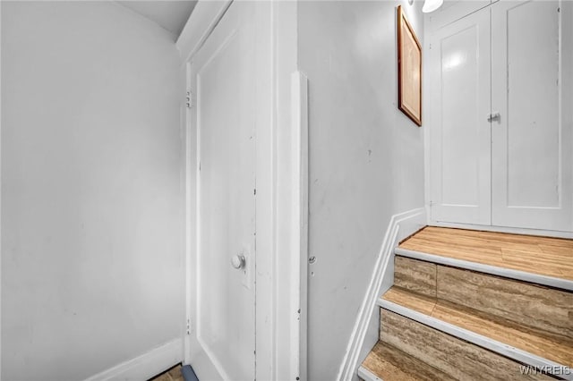 staircase featuring baseboards and wood finished floors